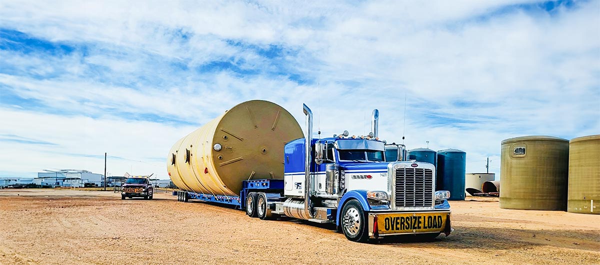 Blue truck transporting large vessel